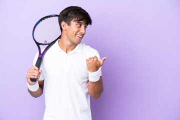 Handsome young tennis player man isolated on ocher background pointing to the side to present a...