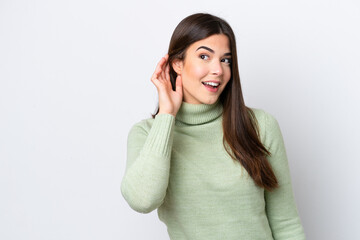Young Brazilian woman isolated on white background listening to something by putting hand on the ear