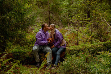 Naklejka na ściany i meble Couple in lilac jackets kissing in the woods, with a dog
