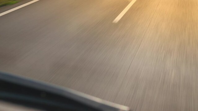 Highway asphalt road with white markings close view from shipment truck hood. Moving motorway close up while riding