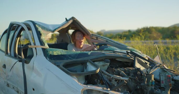 A woman sitting in a broken car after a car accident miraculously survived and cannot believe that she remained alive, looking around her in a state of shock