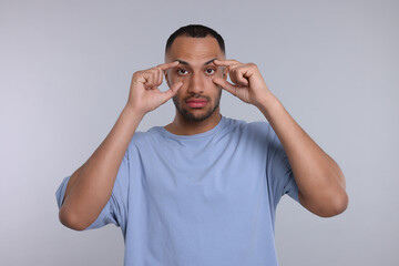Fototapeta premium Tired man on light grey background. Insomnia problem