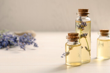 Essential oil and lavender flowers on white wooden table, closeup. Space for text