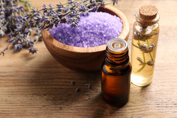 Fototapeta na wymiar Bowl of sea salt, essential oil and lavender flowers on wooden table