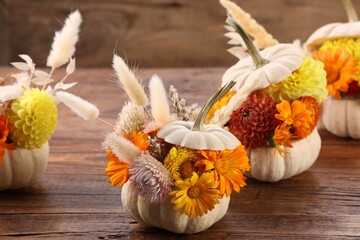 Composition with small pumpkins, beautiful flowers and spikelets on wooden table, closeup