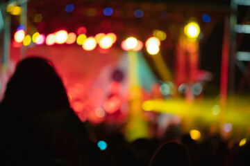 Silhouettes of concert crowd with stage lights, out of focus blurred photo
