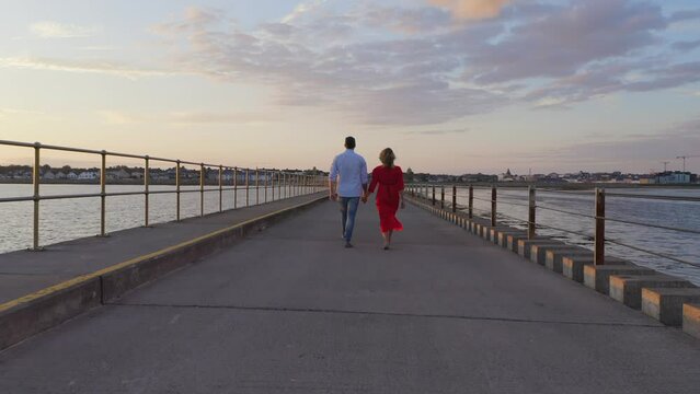 Red dress adds color to serene causeway walk. Slomo, sunset. Galway