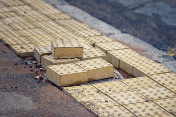 Paving work, tactile paving installation, yellow bumpy blocks for blind people on sidewalk, walkway...