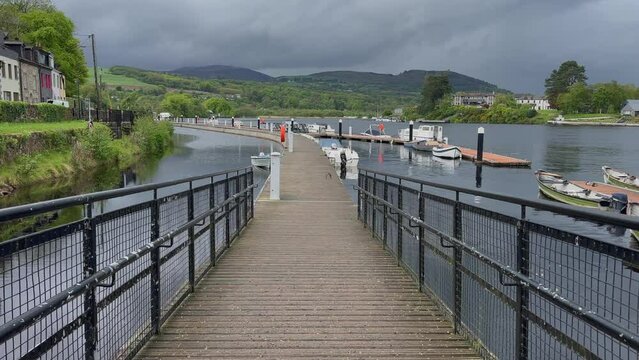 POV walking down ramp to floating marina dock on river in lush Ireland