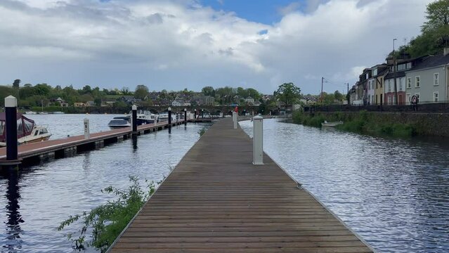 POV walking on floating pier on river in Killaloe near old arch bridge