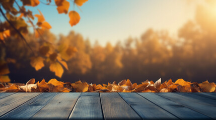 Empty wooden table top, deck with dried fallen maple leaves on in blurred forest background
