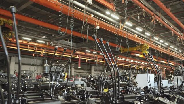 Closed assembly shop for automotive production with ready-made chutes and with lifting mechanisms and tubes for pneumatic impact wrenches. Large production with lights and hoists on in factory.