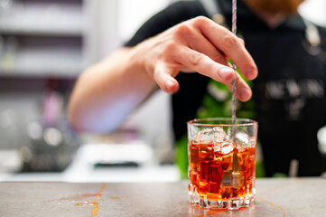 bartender hand making negroni cocktail in bar