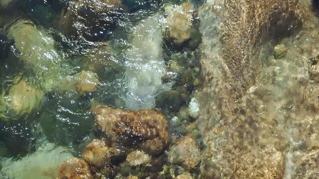 Mountain river, a spring in the mountains.clear water flows between the stones and sparkles in the sun, view from above
