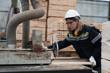 Female carpenter factory worker using wood rolling machine for process timber at manufacturing lines in wooden warehouse storage plant