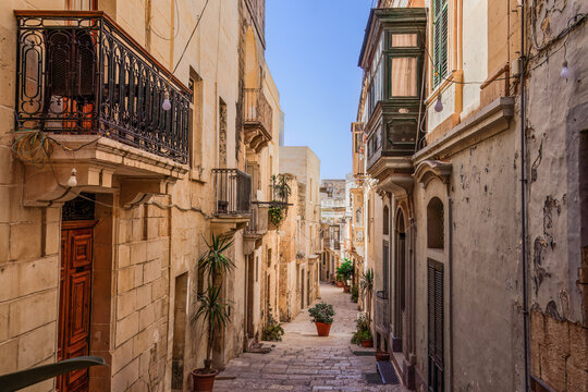 Traditional Maltese limestone buildings with coloured balconies in the vibrant alleys of the old city of Birgu (Citta Vittoriosa), Malta, Mediterranean