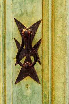Traditional brass door knocker detail with Maltese cross design outside a building in the alleys of the old city of Birgu (Citta Vittoriosa), Malta, Mediterranean