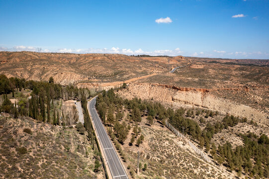 Drone aerial view of a road crossing a desert like landscape near Francisco Abellan Dam and Reservoir, Granada, Andalusia