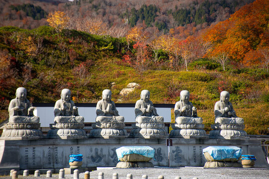 Row of six shizo statues with a beautiful autumnal landscape in the background, Osorezan Bodaiji Temple, Mutsu, Aomori prefecture, Honshu, Japan