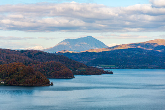 View over the forest slope of Lake Toya in the evening with volcano in the distance, Abuta, Hokkaido, Japan