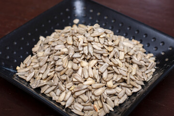 Pile of peeled sunflower seeds on black plate.