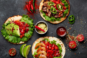 Tacos with salsa, vegetables and avocado on black background