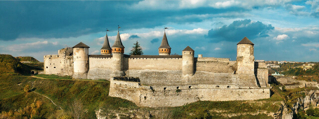 An ancient defensive fortress on a rock in the city of Kamianets-Podilskyi in Ukraine - obrazy, fototapety, plakaty