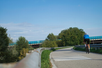 Male athlete on road bicycle rear view during a sunny day