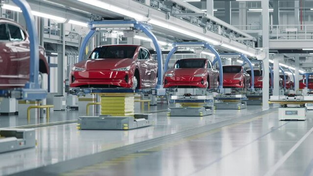 EV Production Line on Advanced Automated Bright Factory. High Performance Electric Car Manufacturing. Car Batteries being Attached to Electric Vehicles on Assembly line. AGV Transport Batteries.