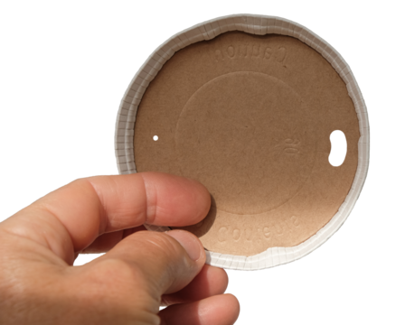 Paper biodegradable lid in the woman's hand. Caution hot contents inscription.