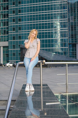 Stylish beautiful blonde walks around the city, great design for any purpose. Attractive elegant woman in jeans.