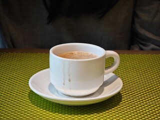 cup of coffee on table, in front of a person