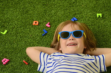 Hebrew alphabet. The boy lies on the grass, letters lie around his head. Concept: education in...