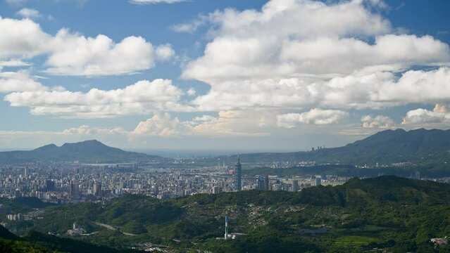 Beautiful white clouds move quickly over the mountains and buildings. A view of Taipei City during the day from Erge Mountain.