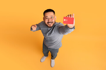 Smiling Young Asian Man Showing Credit Card At Camera