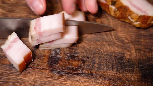 Slicing of salted pork fatback on cutting board, close-up. Ukrainian traditional food - salo