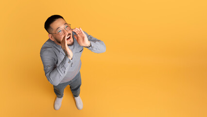 Excited Young Asian Man With Hands Near Mouth Making Announcement