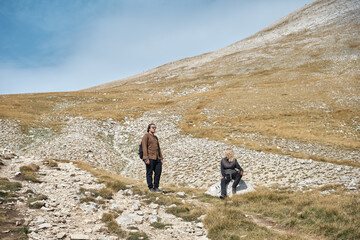 An adult woman and a man rest on a pass during a hike , active recreation in Pirin National Park