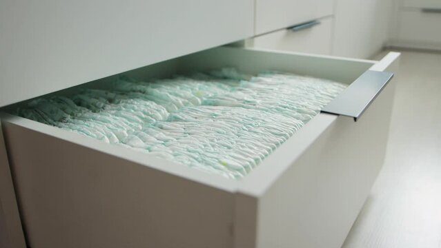 opening of a chest of drawers with baby diapers that absorb moisture, protection against leakage. Hygiene for children, close-up