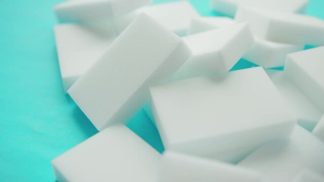 Lots of melanin white sponges for cleaning dirt and stains on a blue background, close-up. Copy space for text