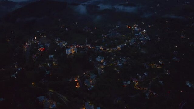 Aerial descending footage of remote town in landscape. High angle view of lighted separate buildings. Ella, Sri Lanka