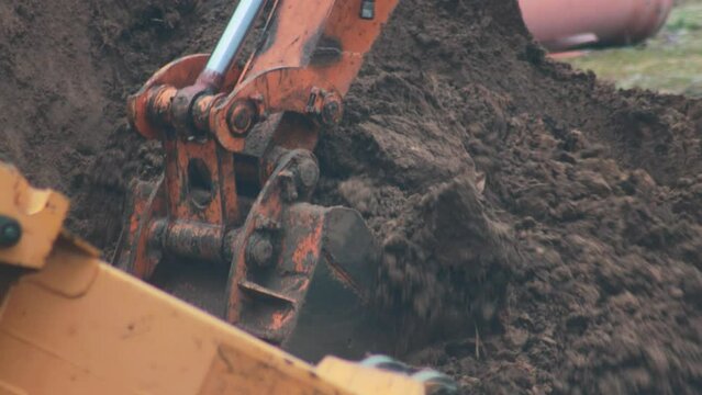 Rotary and telescopic excavator bucket picks up soil for pipeline replacement