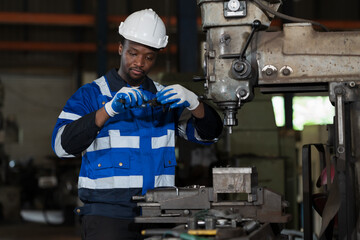 Male engineer worker working with lathe machine in industry factory, wearing safety uniform, helmet. Male technician worker maintenance parts of machine in workshop plant