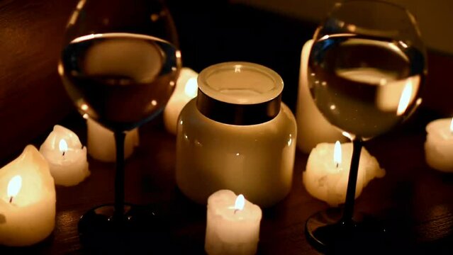Two glasses of white wine and candles in the dark. The wind blows out the candles. Close-up. Romantic dinner