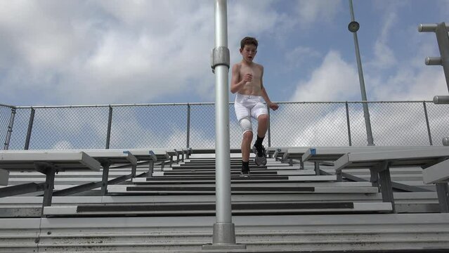 Male youth football player running up and down stadium bleachers for exercise training