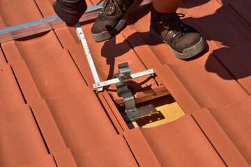 Dachdecker beim Aufbau einer Photovoltaikanlage auf einem neu gedeckten Ziegeldach: Justage und...