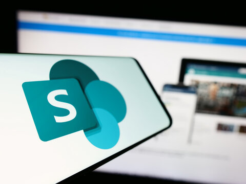 Stuttgart, Germany - 09-21-2023: Cellphone with logo of collaborative platform Microsoft SharePoint on screen in front of business website. Focus on left of phone display.
