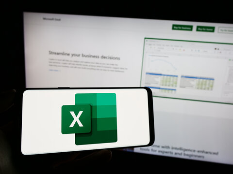 Stuttgart, Germany - 09-21-2023: Person holding cellphone with logo of spreadsheet editor Microsoft Excel on screen in front of business webpage. Focus on phone display.