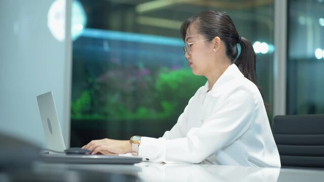 happy asian business woman  using computer on desk looking at wrist watch check time working to break out office