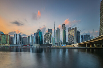 Port entrance in Dubai in the evening. Skyline view. Evening sun with clouds over city skyline of United Arab Emirates. City center with skyscrapers of business and office buildings at sunset